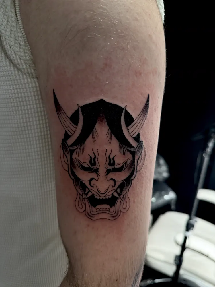 Hannya mask tattoo with black flowing hair on the upper arm