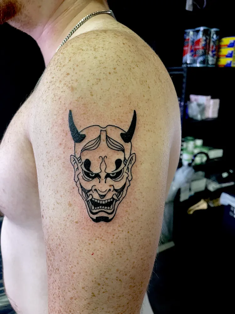 Black Hannya mask tattoo with solid black horns on the shoulder