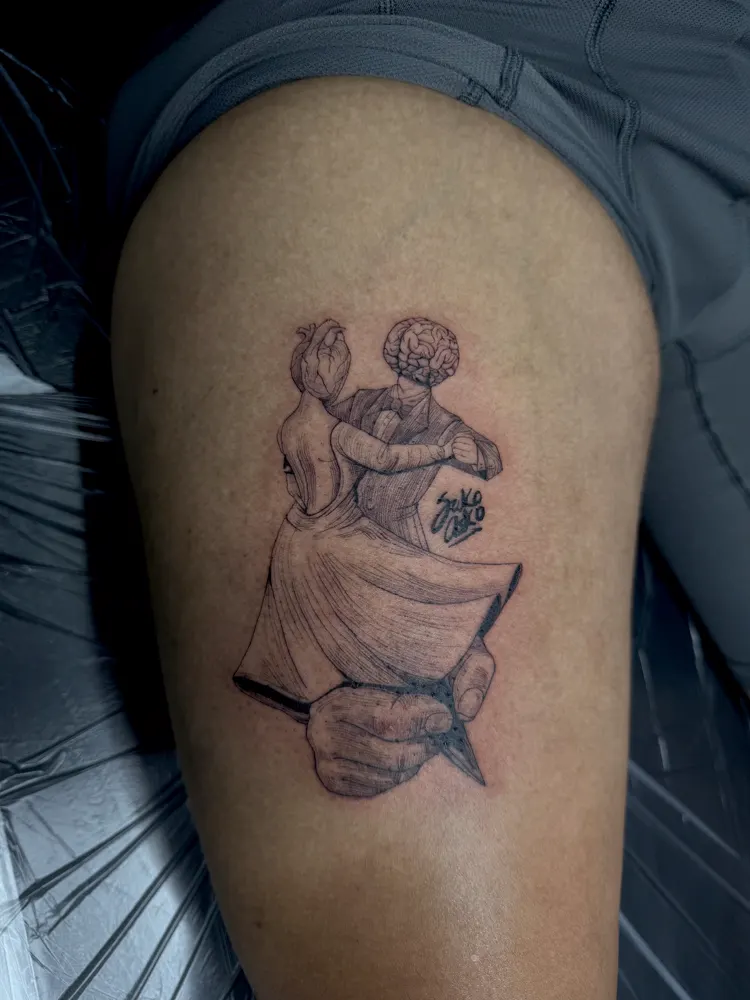 Dancing couple tattoo with heart and brain heads on the thigh