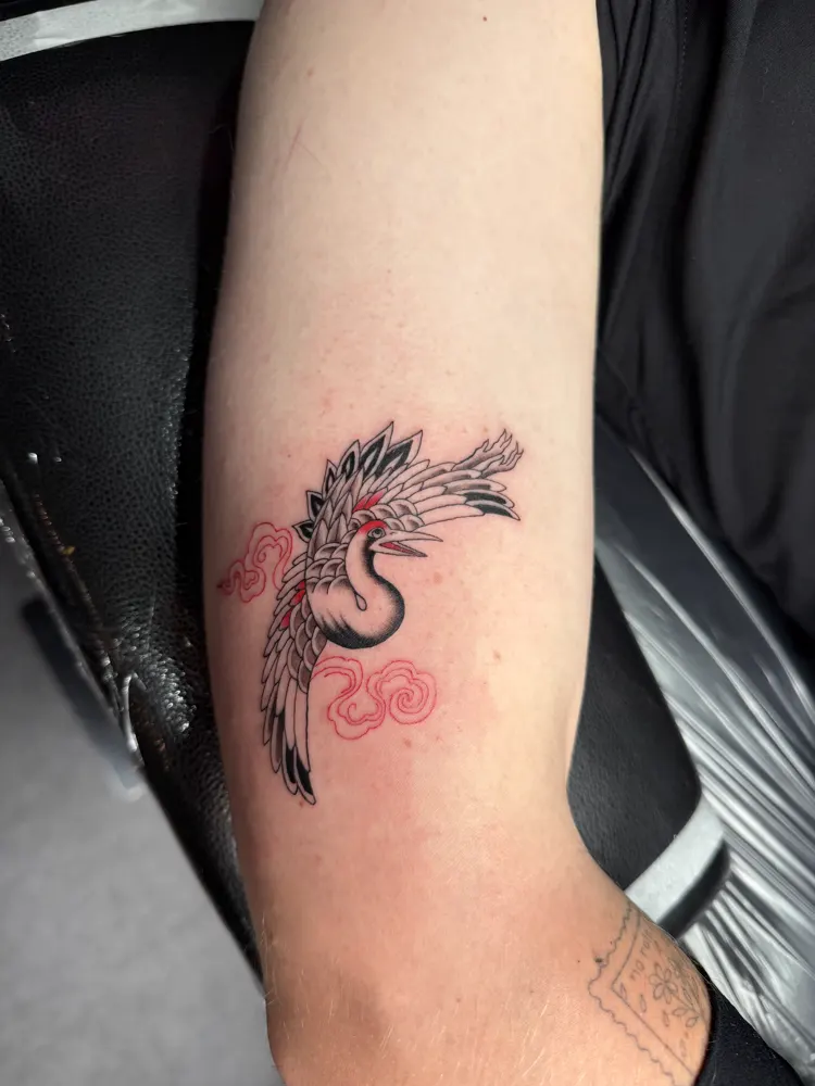Japanese crane tattoo with red clouds on the upper arm