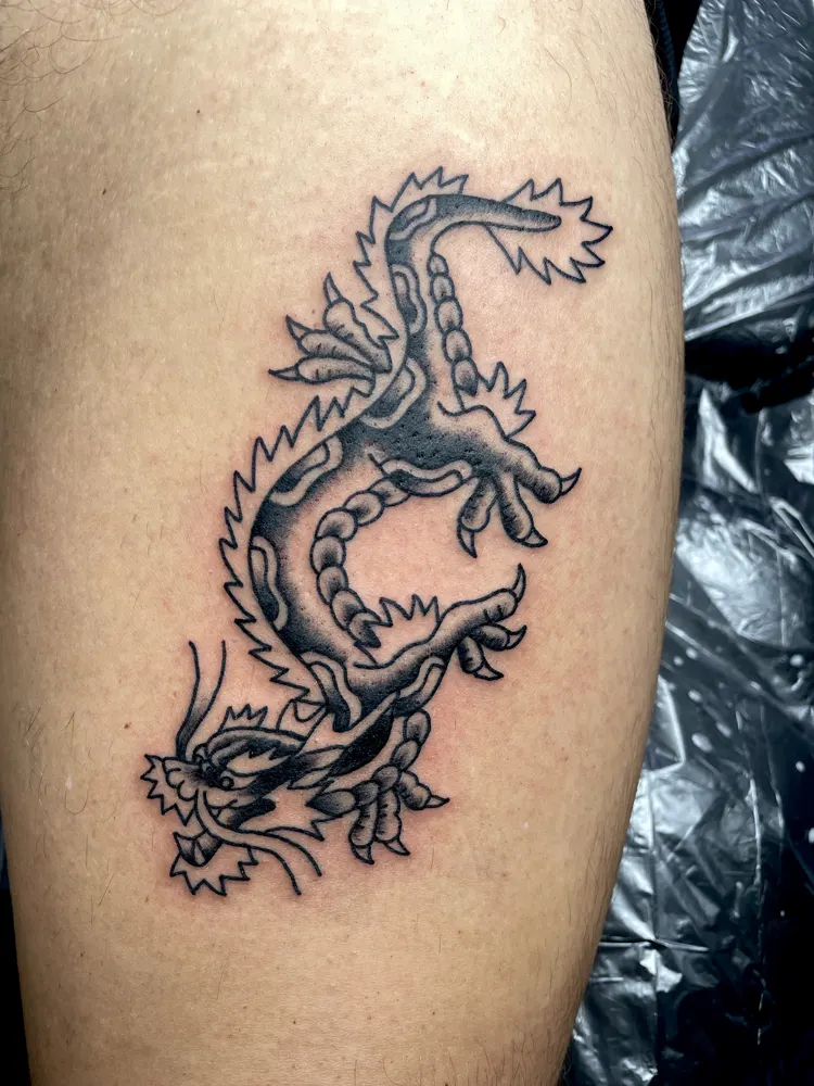 Japanese dragon tattoo in black and grey on the thigh