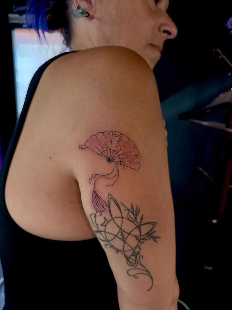 Japanese folding fan tattoo with pink cherry blossoms on the upper arm