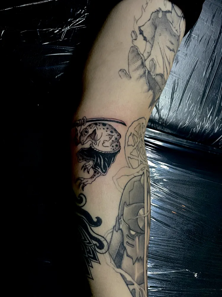 Japanese frog with katana tattoo in black linework on the arm
