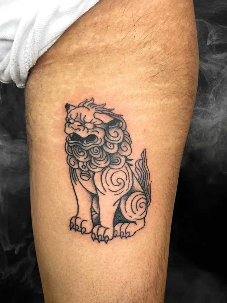 Sitting shishi lion tattoo in black linework on the thigh